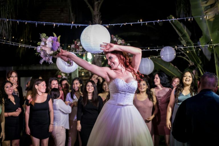 Bride dancing joyfully at her wedding reception surrounded by friends and family.