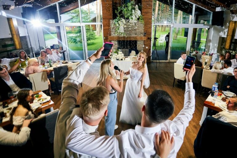 Wedding celebration with guests taking photos of bride and groom in a bright, modern venue.