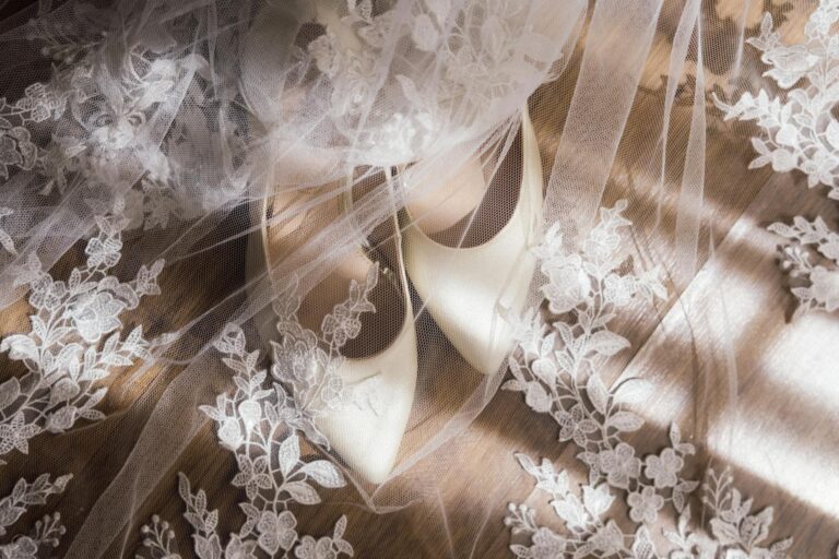 Elegant white wedding shoes with lace veil for bridal photos.