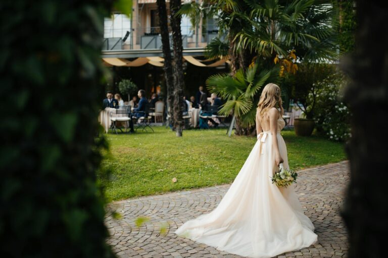 Bride in a wedding dress holding a bouquet in a lush outdoor garden.