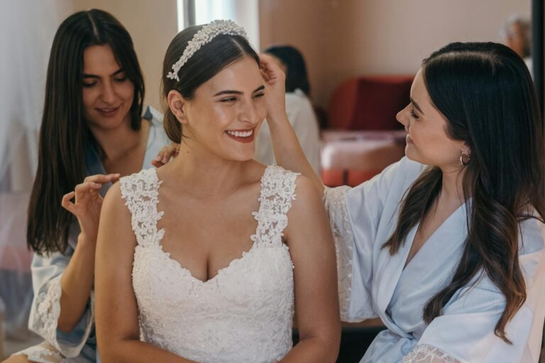 Bride smiling as her bridesmaids help her prepare for the wedding.