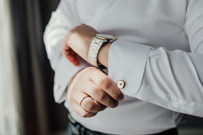Close-up of man adjusting cufflinks on a white dress shirt.
