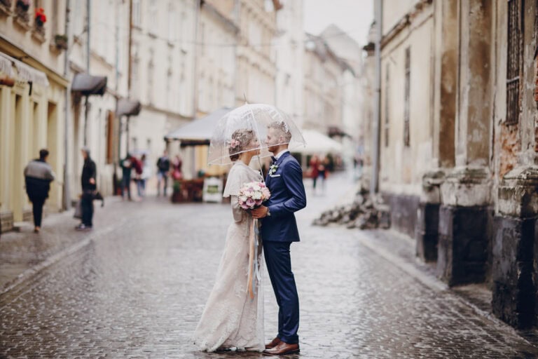 Wedding couple under umbrella in rainy street, Fontainebleau.