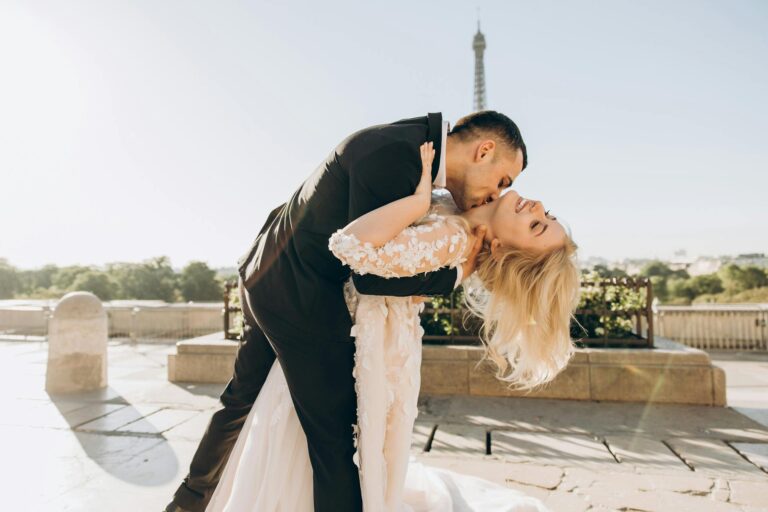 Romantic bride and groom sharing a dance on a scenic terrace with the Eiffel Tower in the background.