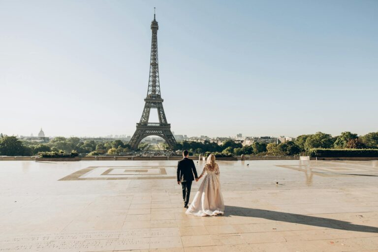 Eiffel Tower with newlywed couple walking hand in hand in Paris.