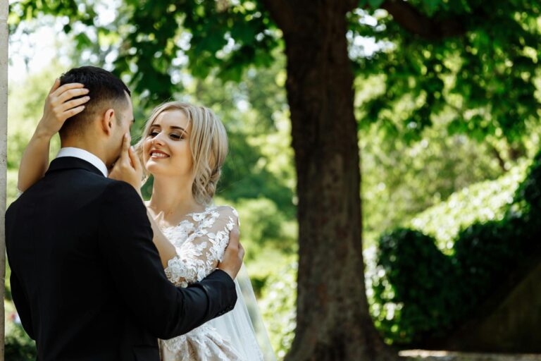 Wedding couple embracing outdoors in a lush green park.